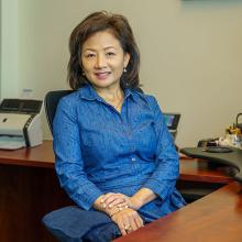 Image of lady in office setting sitting at her desk.
