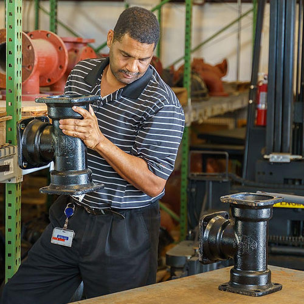 Image of warehouse manager lifting pipe parts from shelf. 