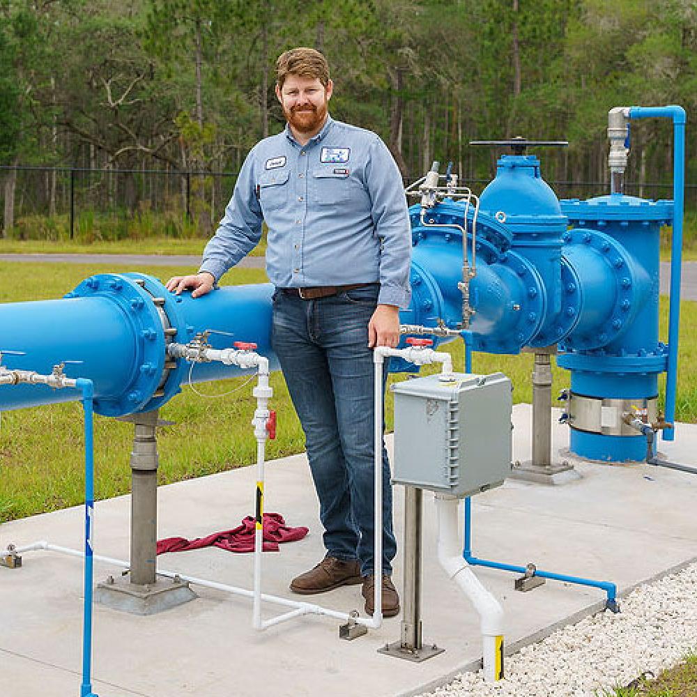 Image of male water plant operator standing near water pipes.