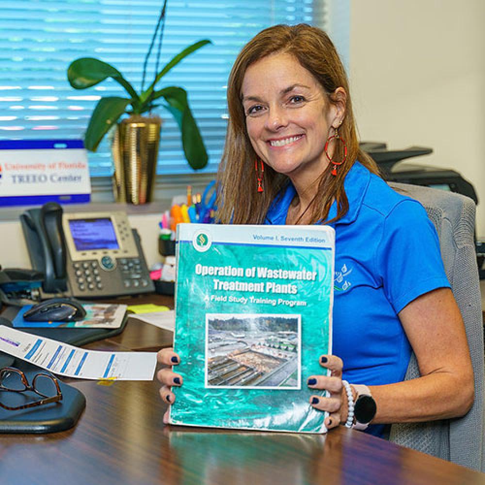 Image of female training coordinator holding classroom book. 