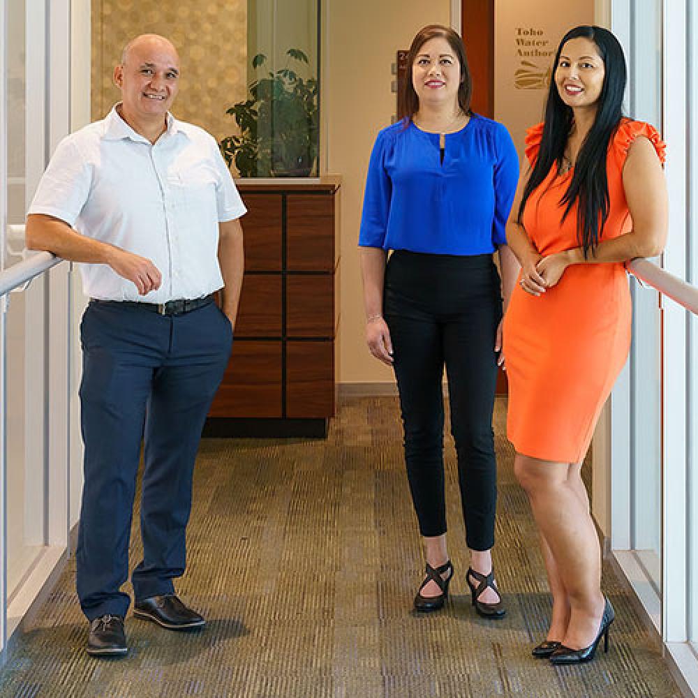 Photo of employees standing together in office setting.