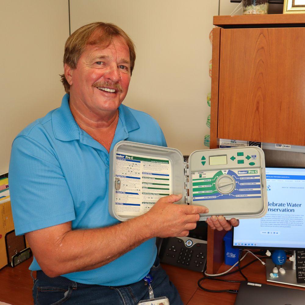 Image of irrigation technician showing an irrigation controller. 