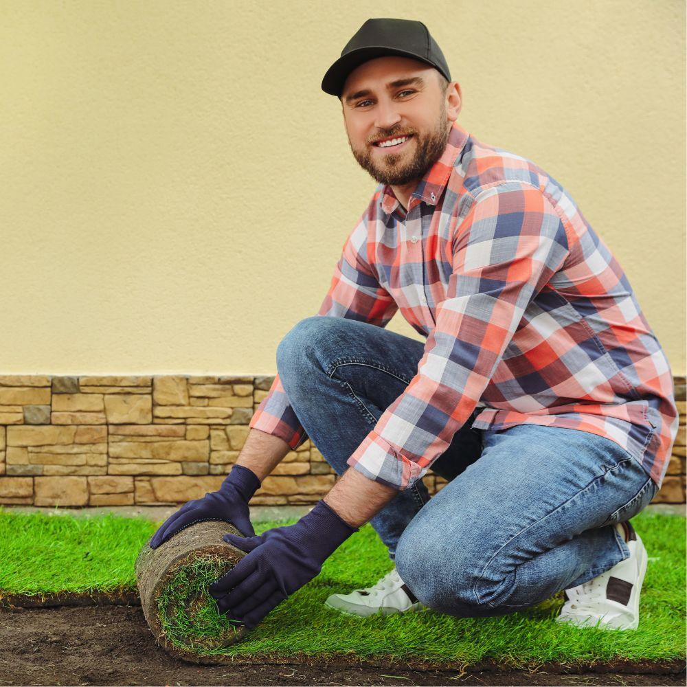 Image of man laying down sod. 