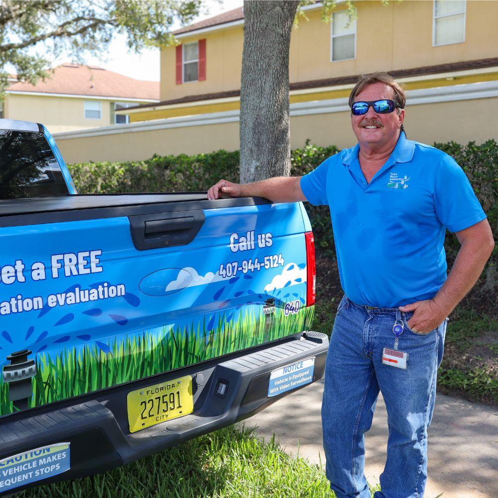 Image of Conservation Specialist standing in front of pick up truck smiling at camera.