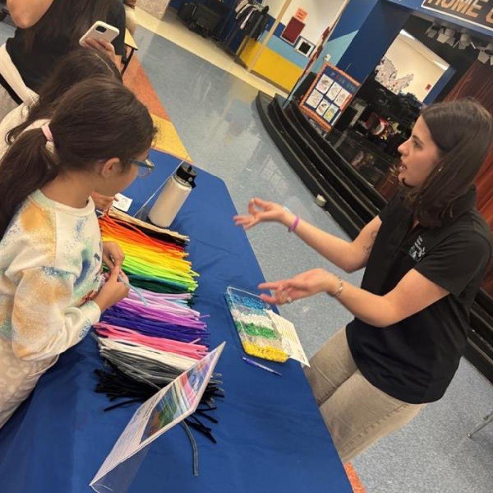 Image of Conservation Specialist explaining an activity to young attendee.