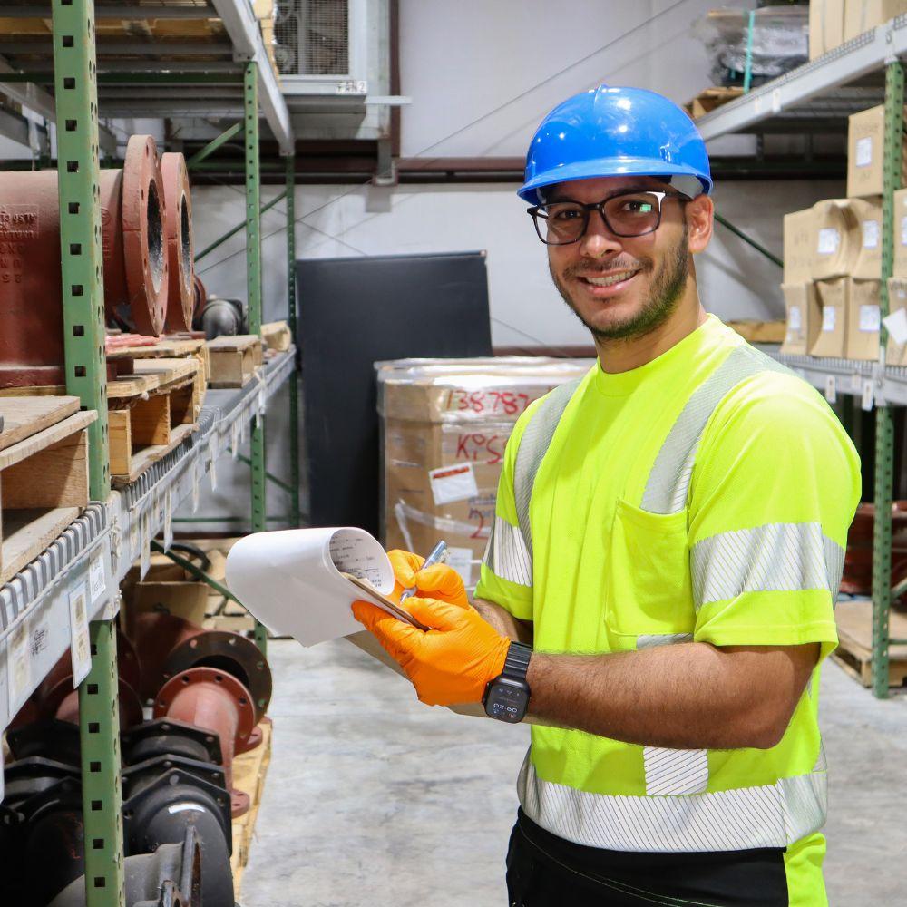 Toho Water Authority warehouse employee smiling at the camera and holding a clipboard.