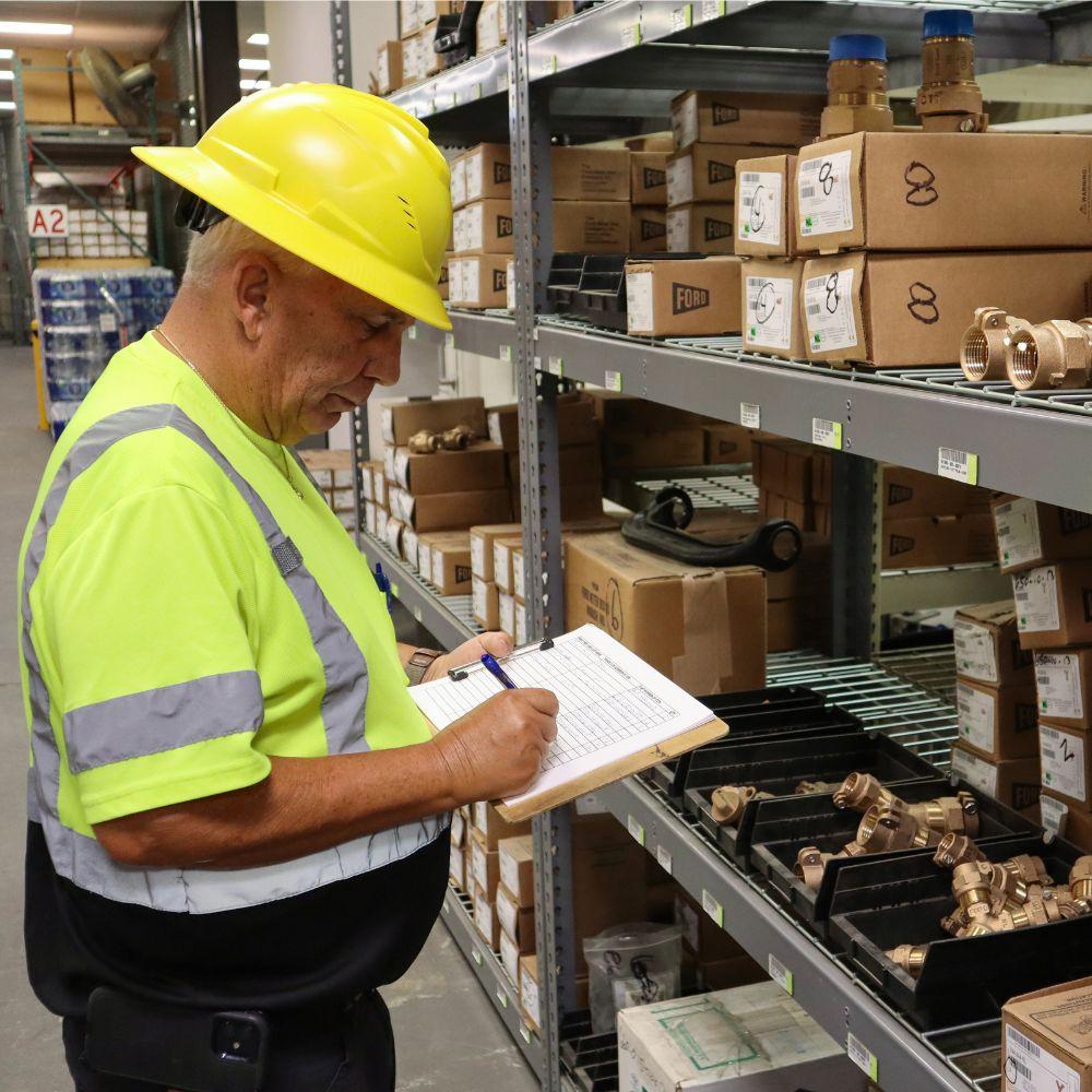 Toho Water Authority warehouse employee holding a clipboard and writing inventory.